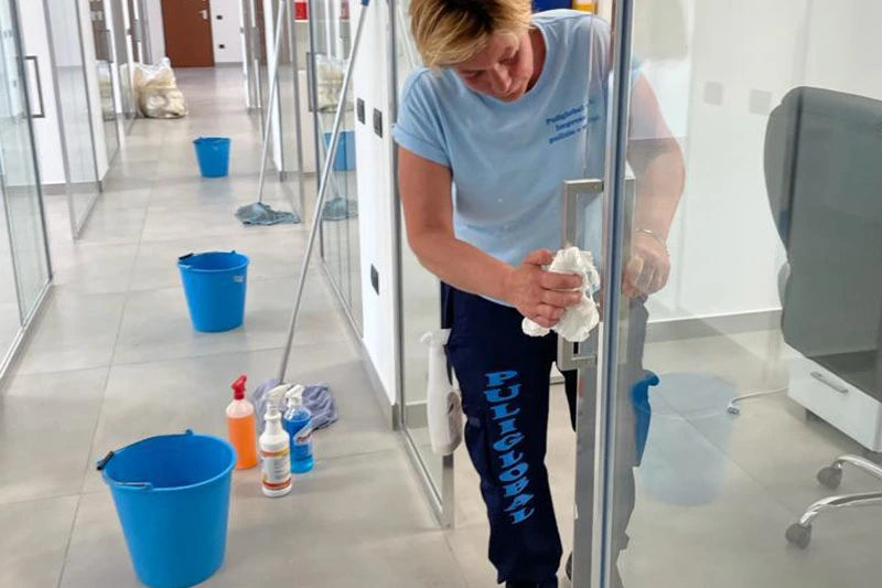 Operatrice Puliglobal pulisce vetri di un ufficio